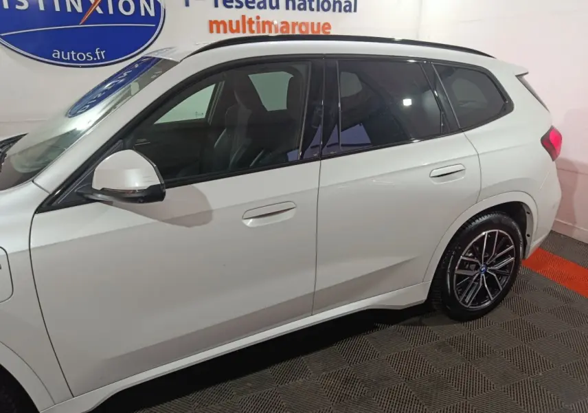 Vue latérale droite d'un BMW X1 blanc 2024 xDrive25e M Sport avec jantes noires et vitres teintées.
