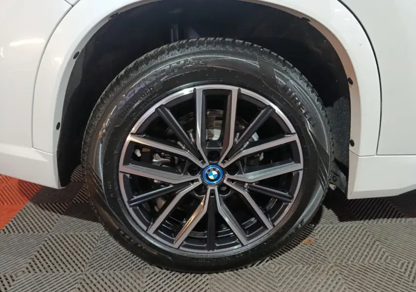 Gros plan sur la roue avant droite noire à jante alliage du BMW X1 blanc xDrive25e M Sport 2024.