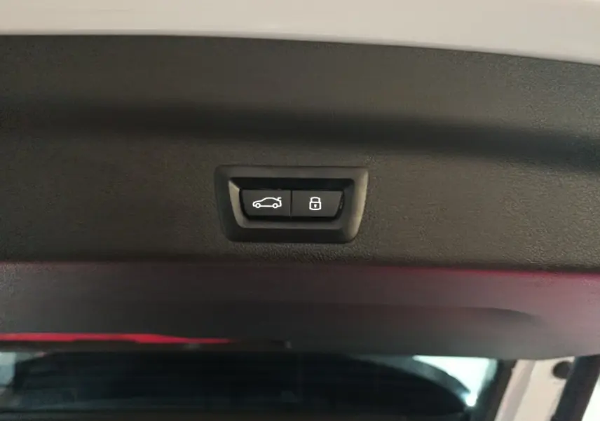 Boutons d'ouverture et de verrouillage du coffre sur la partie intérieure du hayon d'un BMW X1 blanc hybride rechargeable.