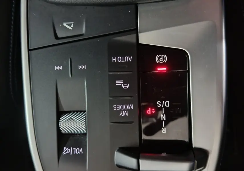 Gros plan sur la console centrale noire et grise du BMW X1 blanc 2024 avec levier de vitesses et commandes tactiles.