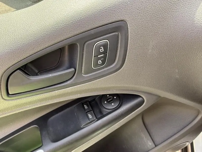 Gros plan sur la poignée intérieure et les commandes de porte côté conducteur du Ford Transit Connect blanc glacier de 2019.