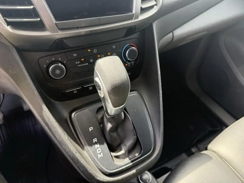 Gros plan sur la commande de boîte automatique noire du Ford Transit Connect blanc, avec tableau de bord et climatisation visible.