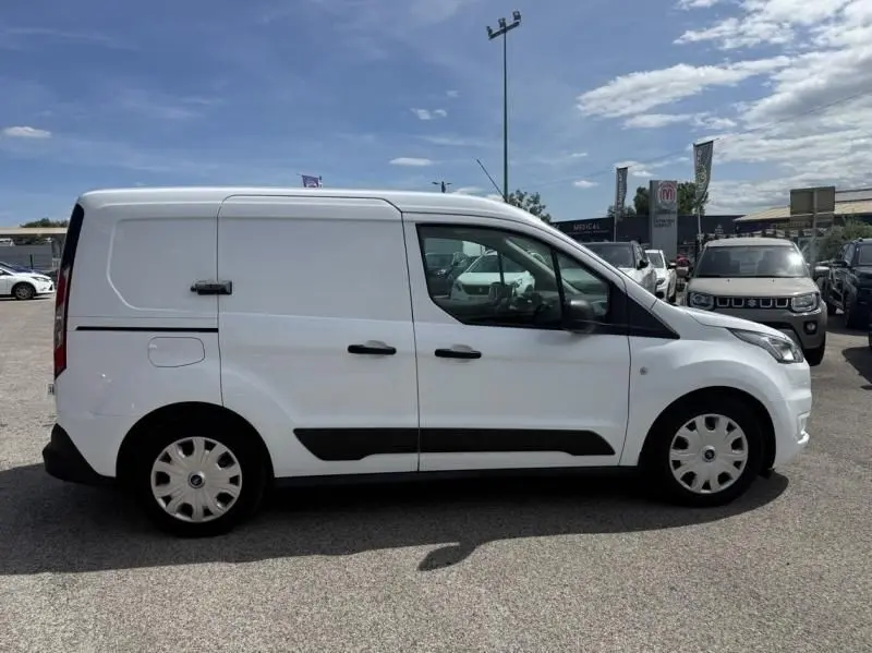 Vue de profil côté droit d’un Ford Transit Connect blanc glacier avec protections noires et jantes acier en parking.