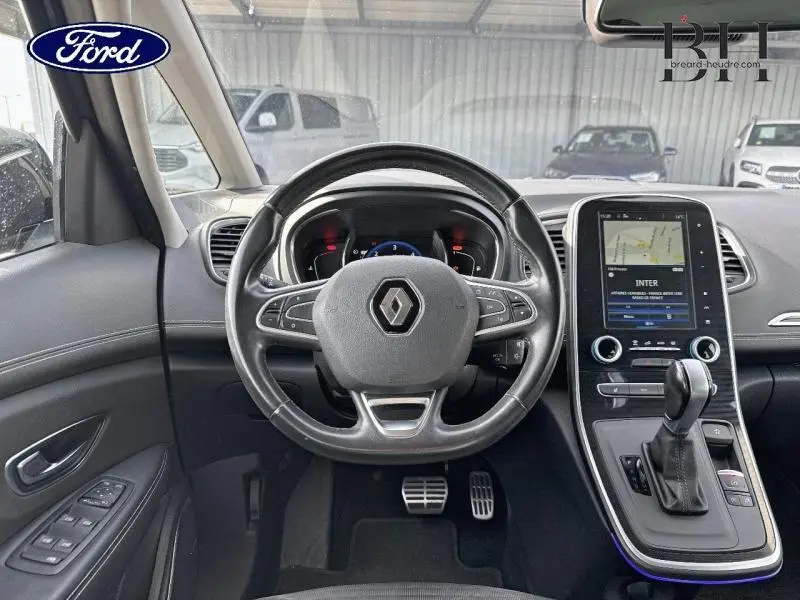 Vue intérieure centrée sur le volant cuir Renault avec tableau de bord et écran tactile vertical du Grand Scenic noir étoilé.