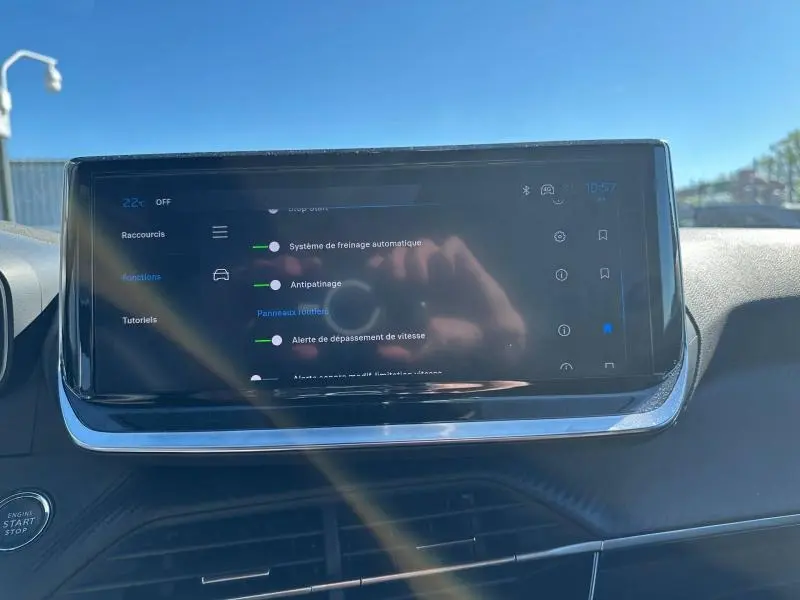 Écran tactile central du tableau de bord du Peugeot 2008 1.2 Hybrid bleu, affichant les réglages d’aides à la conduite.