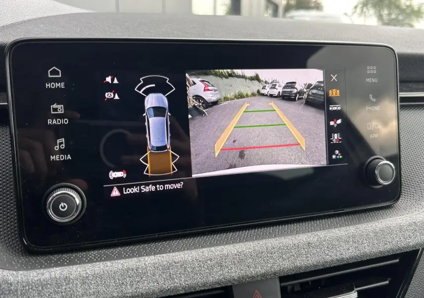 Écran central de la Skoda Scala blanc montrant la caméra de recul avec lignes de guidage colorées.