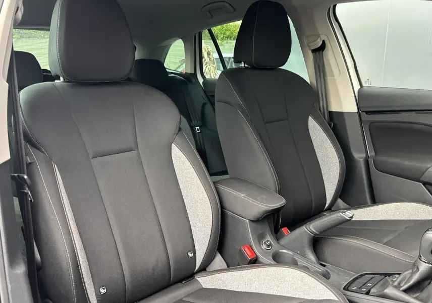 Vue intérieure sur les sièges avant tissu noir et gris du Skoda Scala TSI 116 DSG7 Sélection, avec accoudoir central.
