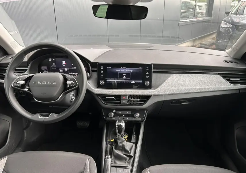 Vue intérieure avant du Skoda Scala blanc Candy 2025, volant cuir multifonctions et écran tactile central visible.