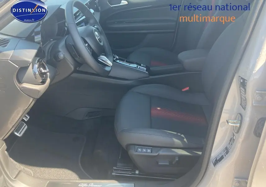Vue intérieure côté conducteur de l'Alfa Romeo Junior 1.2 hybride 2026, sièges noirs et tableau de bord moderne.