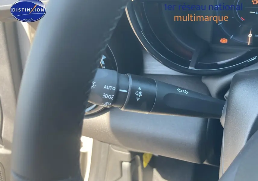 Gros plan sur le commodo d’éclairage et clignotants derrière le volant d’une Alfa Romeo Junior ivoire et noir.