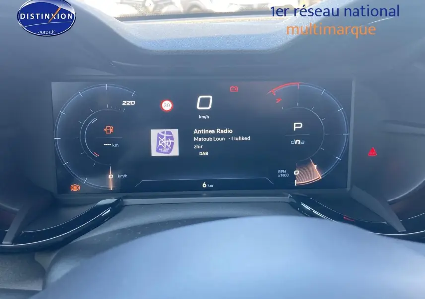 Vue rapprochée du tableau de bord numérique de l'Alfa Romeo Junior 1.2 hybride, affichant la radio et l'indicateur de vitesse.