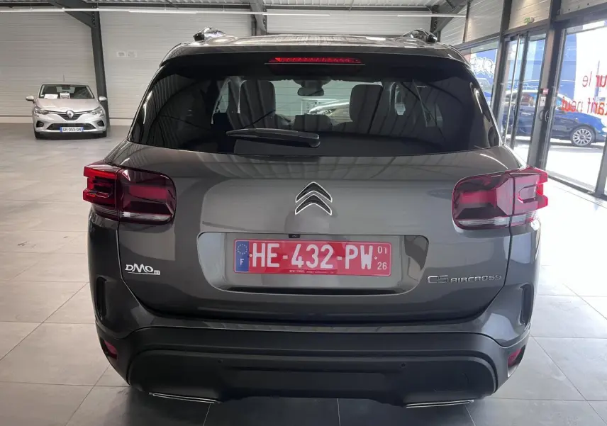 Vue arrière d'un Citroën C5 Aircross gris platinium en showroom, avec feux arrière LED et double sortie d'échappement.
