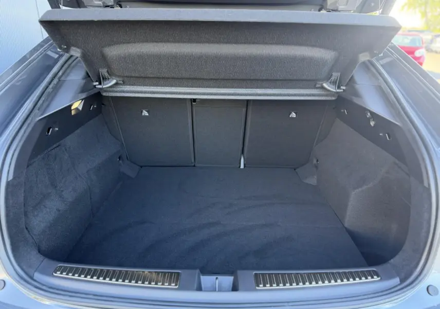 Coffre ouvert vu de l'arrière d'une Renault Rafale gris schiste avec hayon électrique, espace de chargement vide et tapis noir.