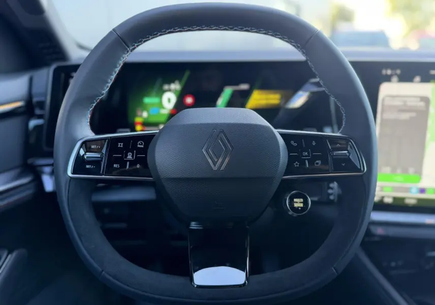 Volant en textile refined grain fin avec logo Renault, sur fond de tableau de bord numérique et écran tactile intérieur.