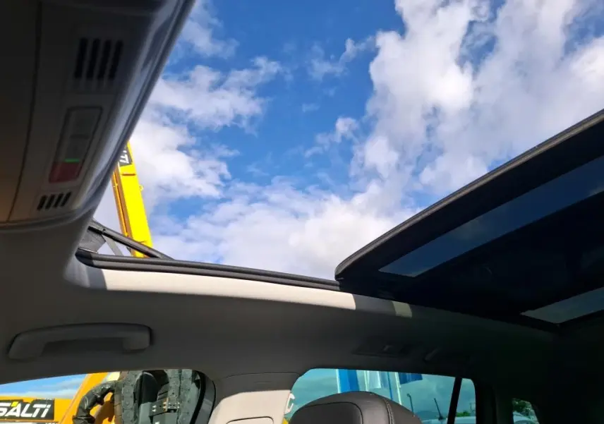 Vue intérieure du toit ouvrant panoramique du Volkswagen Tiguan gris clair 2022, avec ciel bleu visible à travers le verre.