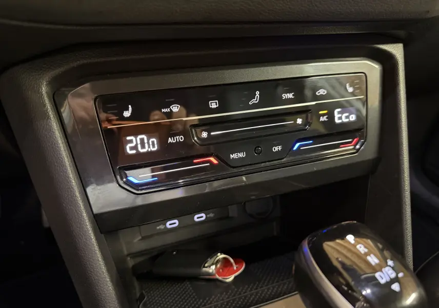 Gros plan sur la console centrale noire du Volkswagen Tiguan 2022, affichant la climatisation digitale et le levier de vitesse automatique.