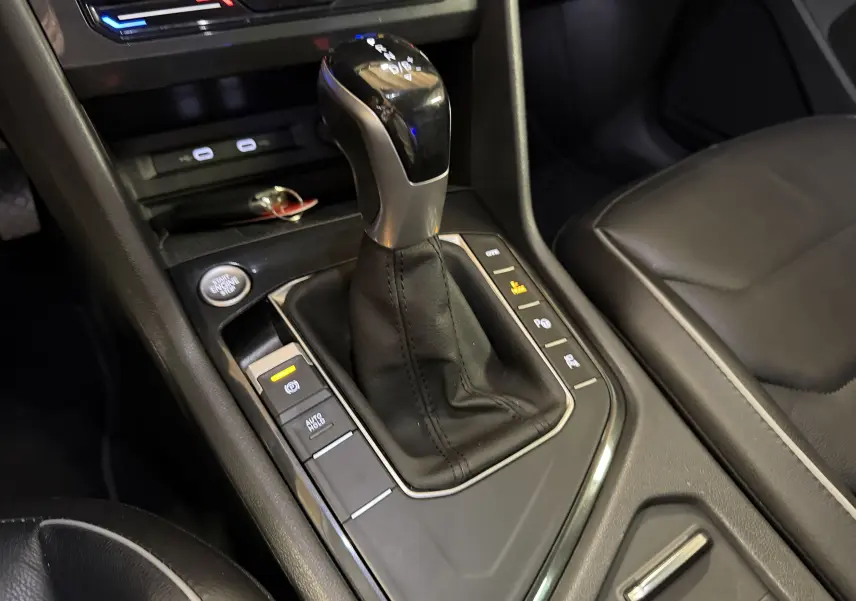 Gros plan sur la console centrale noire du Volkswagen Tiguan 1.4 e-Hybrid 2022, mettant en valeur le levier de vitesse automatique.