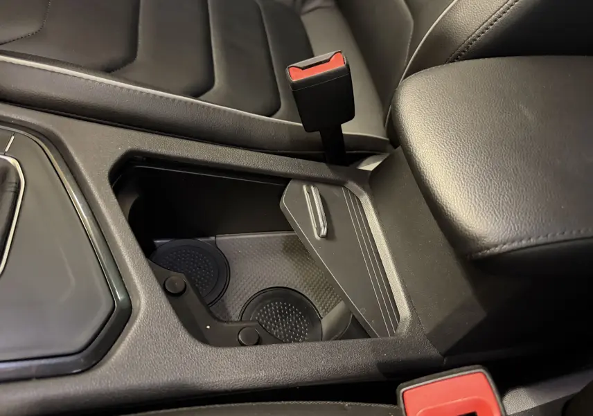 Gros plan sur la console centrale noire du Volkswagen Tiguan 2022, avec porte-gobelets et accoudoir en cuir.