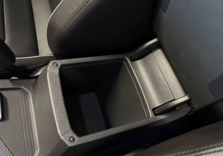 Vue rapprochée du rangement central ouvert en plastique noir à l'intérieur du Volkswagen Tiguan 1.4 E-HYBRID 2022.