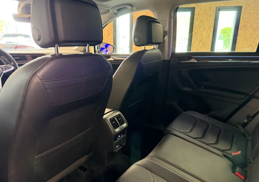 Vue intérieure arrière du Volkswagen Tiguan 1.4 E-Hybrid 2022, sièges en cuir noir et console centrale avec aérateurs.