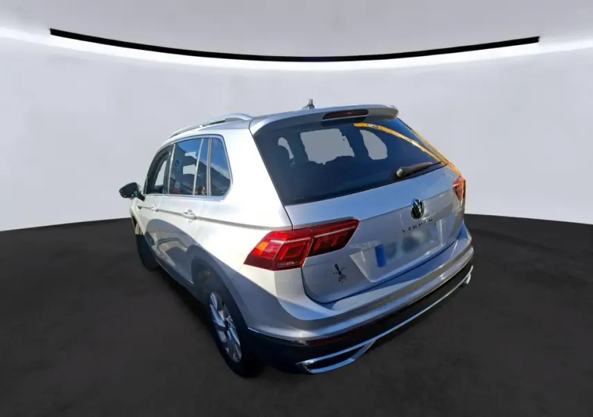 Vue 3/4 arrière droite d'un Volkswagen Tiguan gris clair 2022 avec feux arrière LED et toit ouvrant apparent.