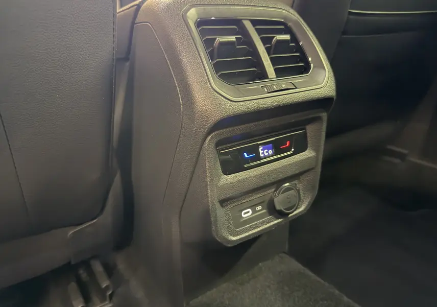 Détail de la console arrière noire du Volkswagen Tiguan 1.4 E-Hybrid 2022 avec commandes de climatisation et prises USB et 12V.