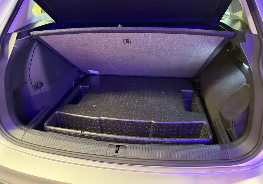 Coffre ouvert du Volkswagen Tiguan gris clair 2022, vue arrière montrant le compartiment de rangement sous plancher.