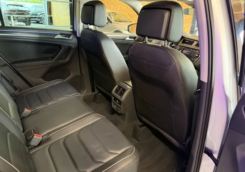 Vue intérieure arrière du Volkswagen Tiguan 1.4 e-Hybrid 2022, sièges en cuir noir et console centrale avec aérateurs.