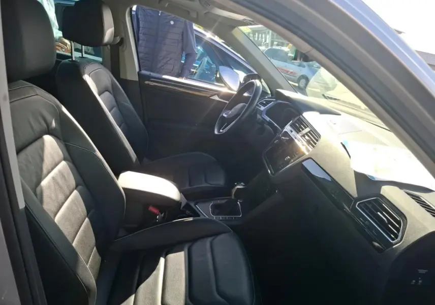 Vue intérieure côté conducteur du Volkswagen Tiguan 1.4 e-Hybrid 2022 avec sièges en tissu noir et tableau de bord moderne.