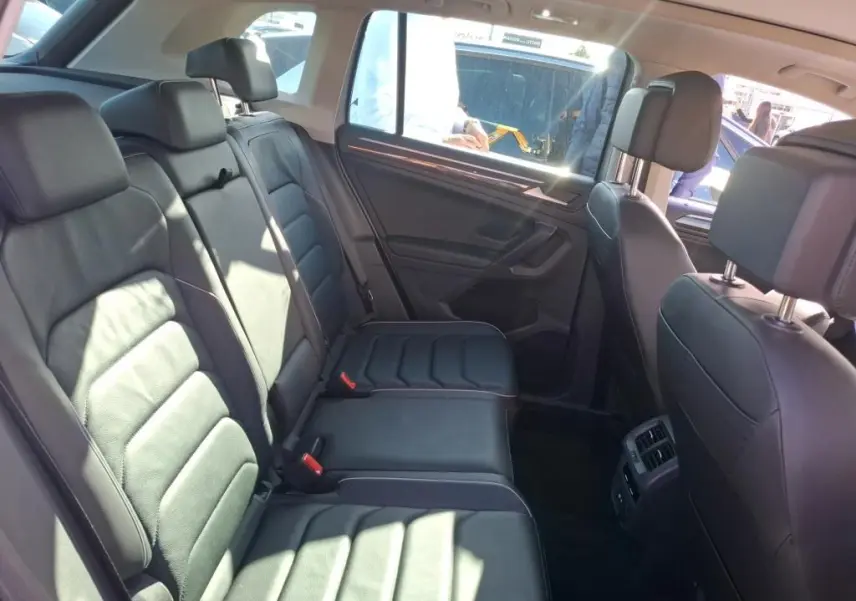 Vue intérieure côté droit des sièges arrière en cuir noir du Volkswagen Tiguan 1.4 E-HYBRID 2022, avec porte et fenêtre visibles.