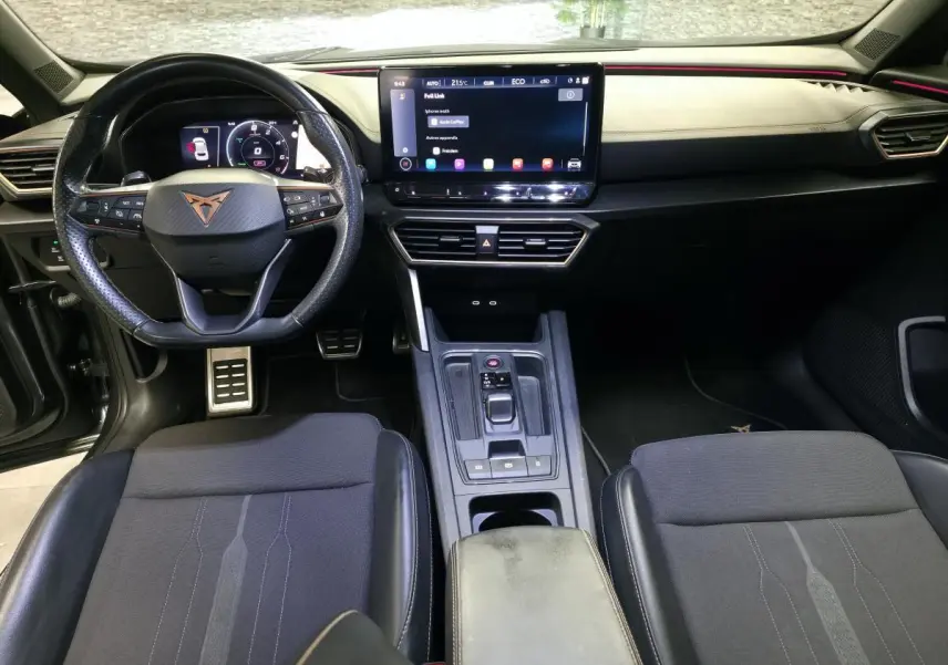Vue intérieure avant du CUPRA Formentor 1.4 e-Hybrid 2024, tableau de bord noir avec écran tactile et volant sport cuir.