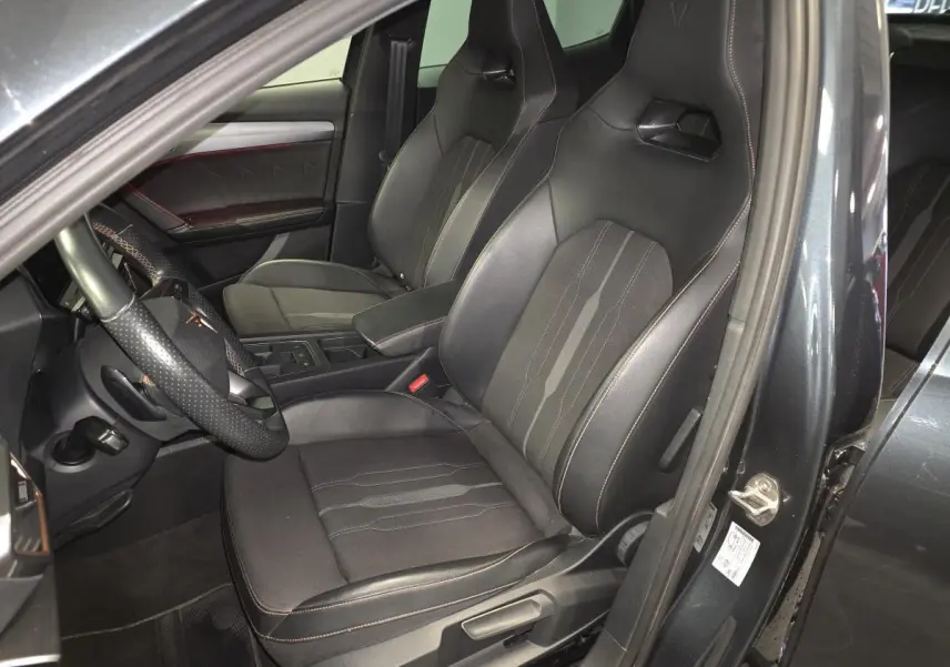 Intérieur du Cupra Formentor 1.4 e-Hybrid 2024 en gris, vue côté conducteur sur sièges baquets noirs avec surpiqûres cuivre.