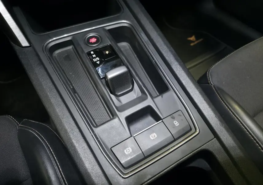 Vue rapprochée de la console centrale noire du CUPRA Formentor 1.4 e-Hybrid avec levier de boîte automatique et boutons fonctionnels.