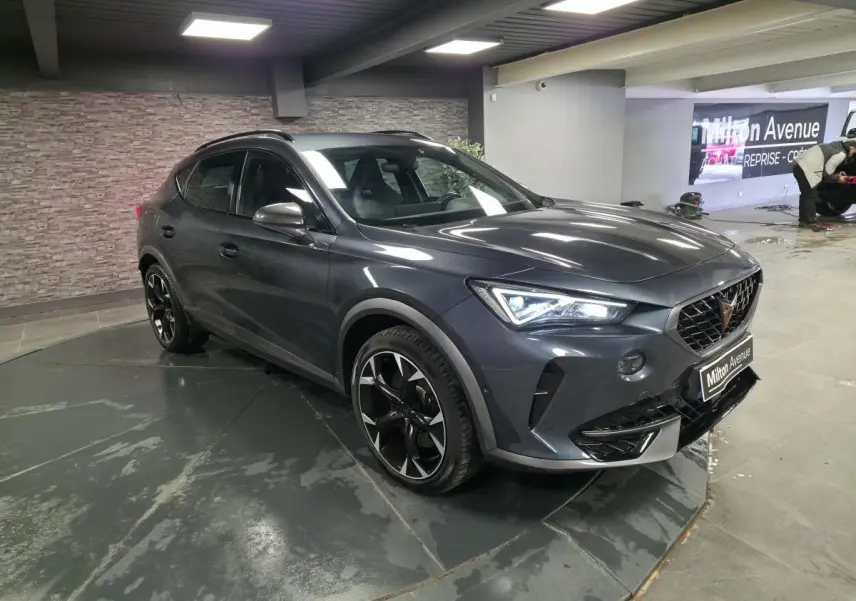CUPRA Formentor gris magnétique en 3/4 avant droit, avec jantes alliage noires et éclairage LED allumé.