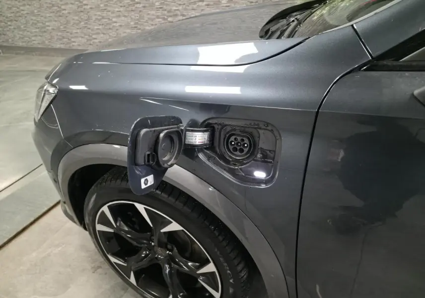 Vue de profil avant droit du CUPRA Formentor gris avec prise de recharge hybride ouverte au-dessus de la roue.