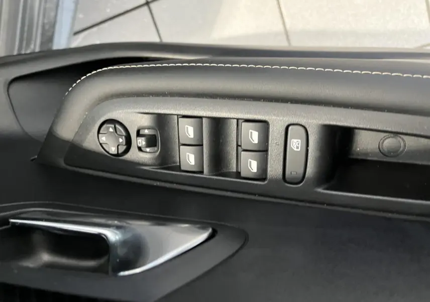 Détail des commandes des vitres et rétroviseurs sur la porte avant gauche d'une Peugeot 208 gris clair Selenium.