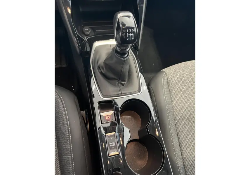 Vue rapprochée de la console centrale noire brillante avec levier de vitesses manuelle et porte-gobelets sur Peugeot 208 gris clair Selenium.