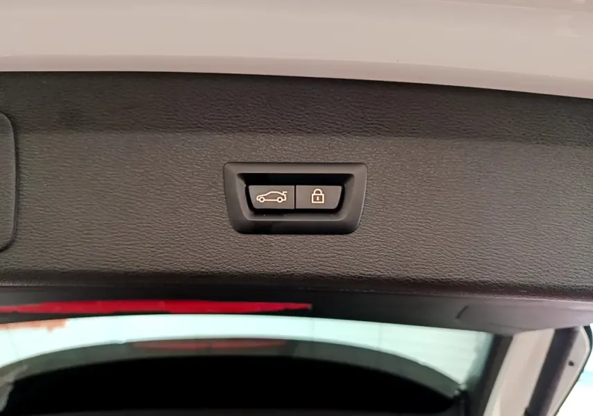 Gros plan sur les boutons d’ouverture et de verrouillage électrique du coffre du BMW X1 blanc, vue intérieure du hayon.