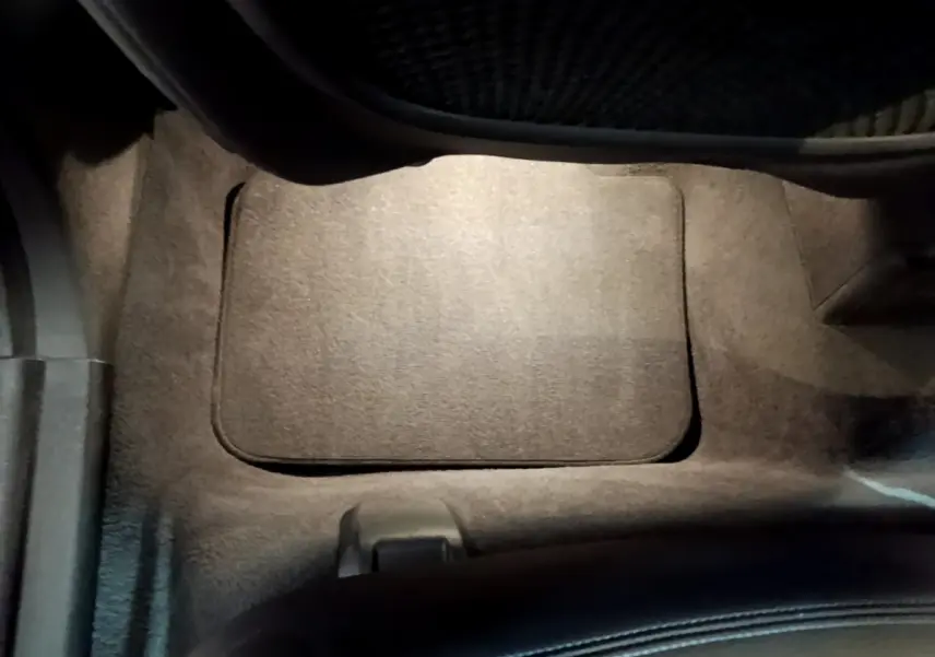Plancher côté passager avant avec tapis noir et partie inférieure du siège dans un BMW X1 blanc.