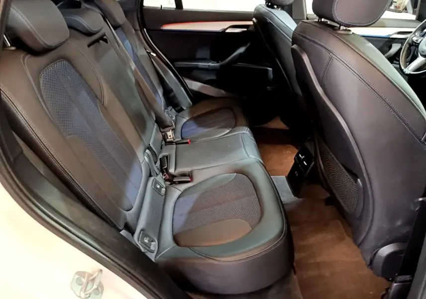 Vue intérieure côté gauche des sièges arrière en cuir noir et tissu bleu du BMW X1 sDrive18i M Sport 2022.