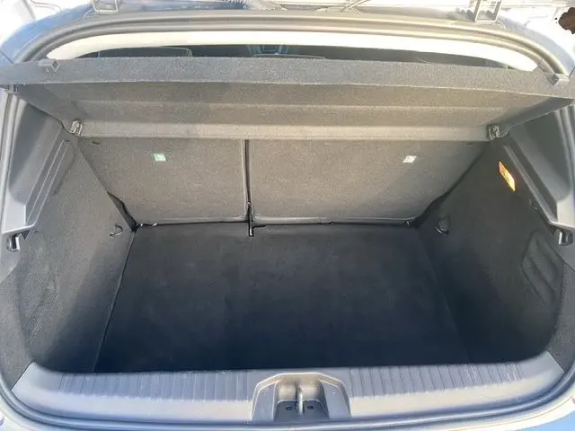 Coffre ouvert vu de l'arrière d'une Renault Clio V gris schiste, montrant un espace de chargement propre et spacieux.