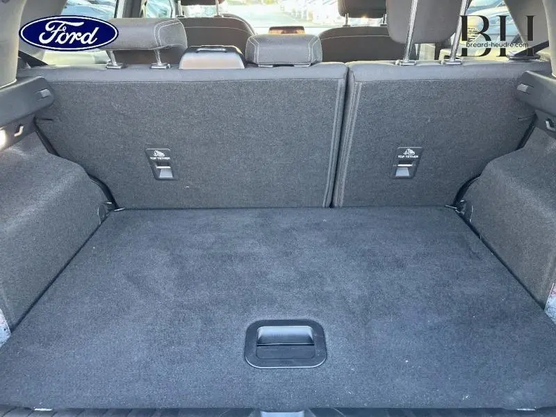 Coffre ouvert vu de l'arrière d'un Ford Puma blanc 2022, avec banquette arrière en tissu noir rabattue.