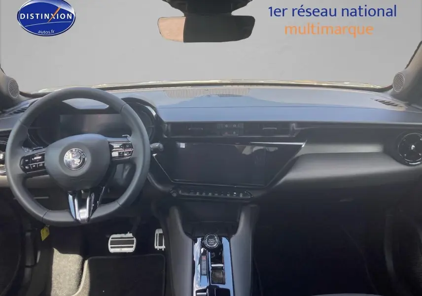 Vue intérieure avant de l'Alfa Romeo Junior 1.2 hybride gris, tableau de bord moderne avec écran tactile et volant multifonction.