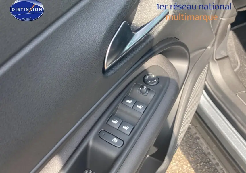 Détail de la commande des vitres sur la porte avant gauche d’une Alfa Romeo Junior gris 2026.