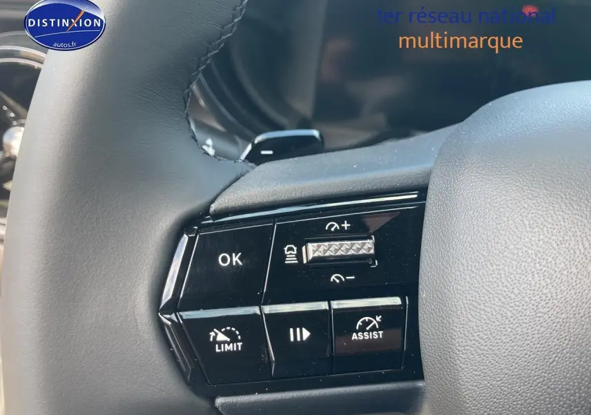Gros plan sur les commandes au volant d'une Alfa Romeo Junior 1.2 hybride grise, avec boutons de régulateur et assistance.