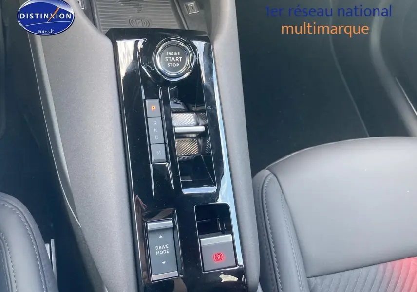 Vue rapprochée de la console centrale noire brillante de l'Alfa Romeo Junior 1.2 hybride avec bouton start et commandes de boîte auto.
