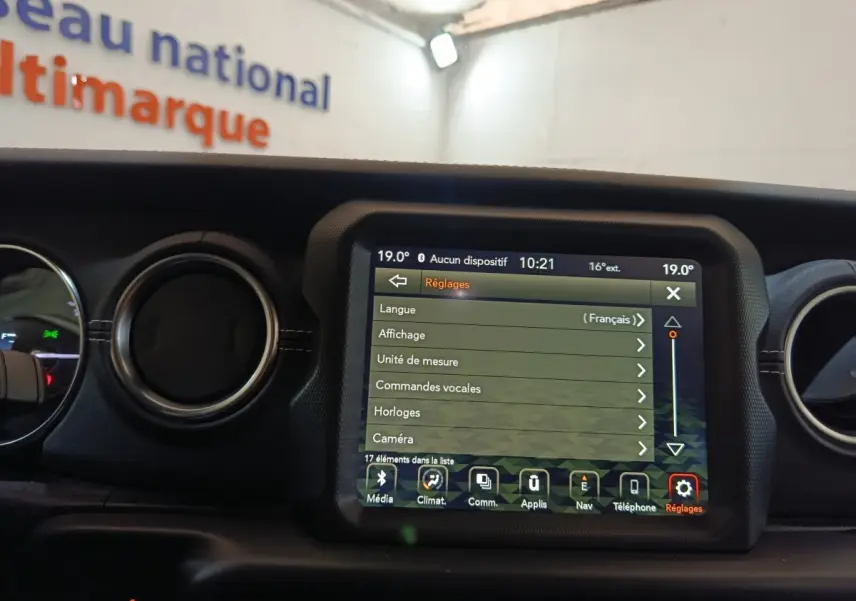 Vue intérieure centrée sur l'écran tactile multifonctions du tableau de bord d'une Jeep Wrangler gris foncé.