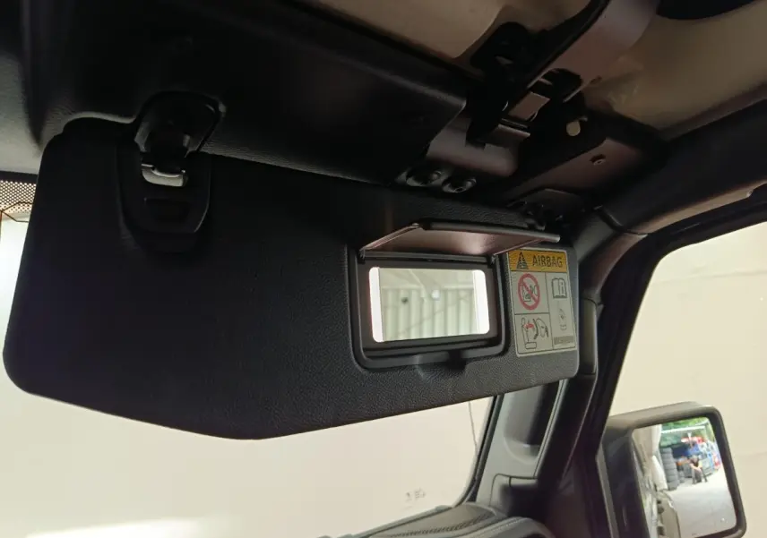 Détail du pare-soleil côté conducteur avec miroir intégré et étiquette airbag dans l’habitacle du Jeep Wrangler gris foncé.