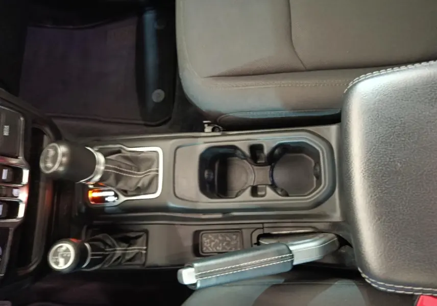 Vue plongeante sur la console centrale noire du Jeep Wrangler 2022 avec levier de vitesses et frein à main cuir.
