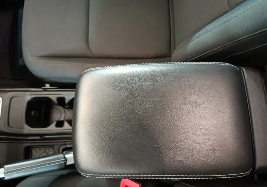Vue rapprochée de l'accoudoir en cuir noir et siège tissu gris foncé à l'intérieur d'un Jeep Wrangler 2022.